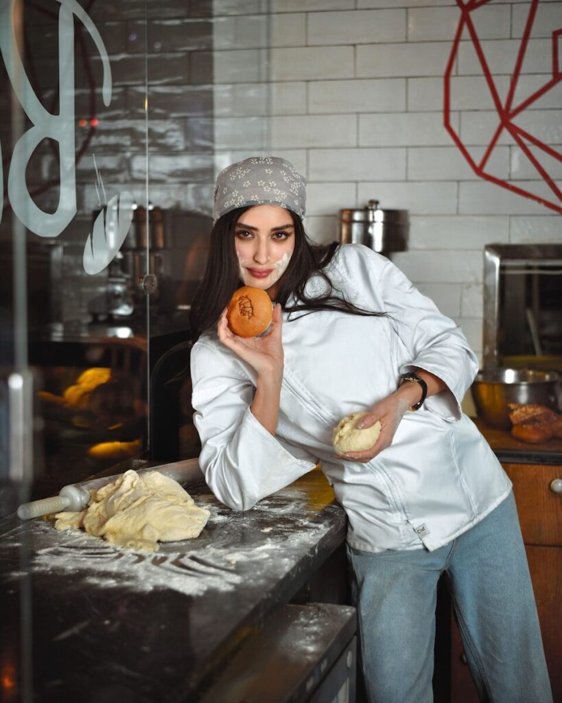 A woman standing in a kitchen holding a doughnut